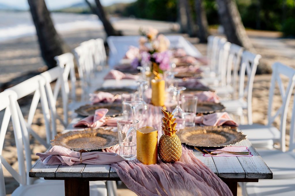 Beach event table styling with a tropical theme of soft ink and gold with gold pineapples
