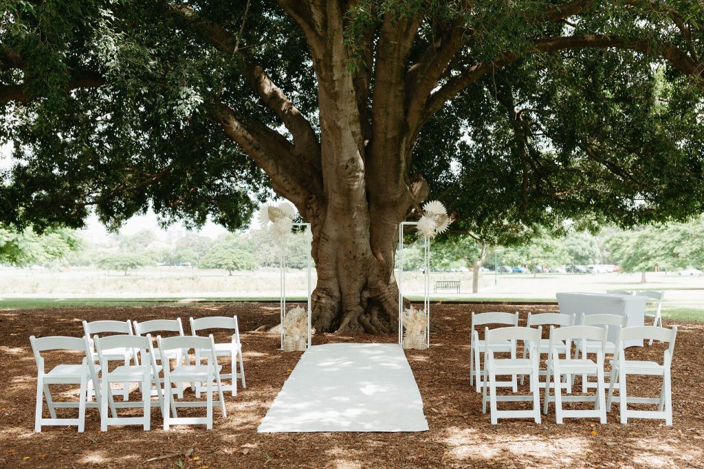 elopement wedding decor and chairs pictured at a beautiful fog tree at New Farm Park with white americana guest chairs