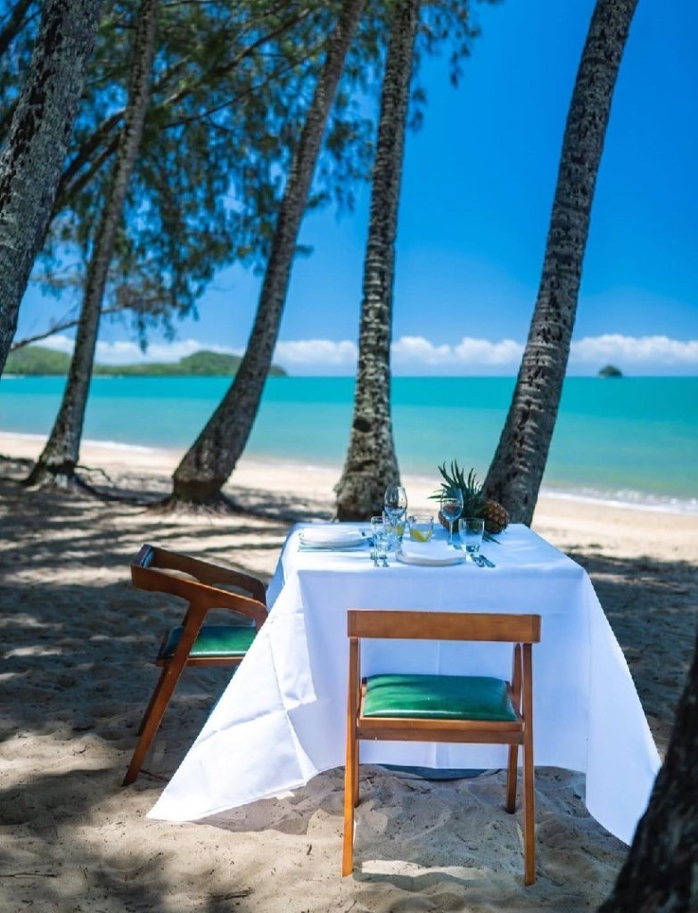 elopement beach wedding reception for two. Table for 2 set up on the beach at Palm Cove beneath the palm trees with the turquoise blue ocean in the backdrop.
